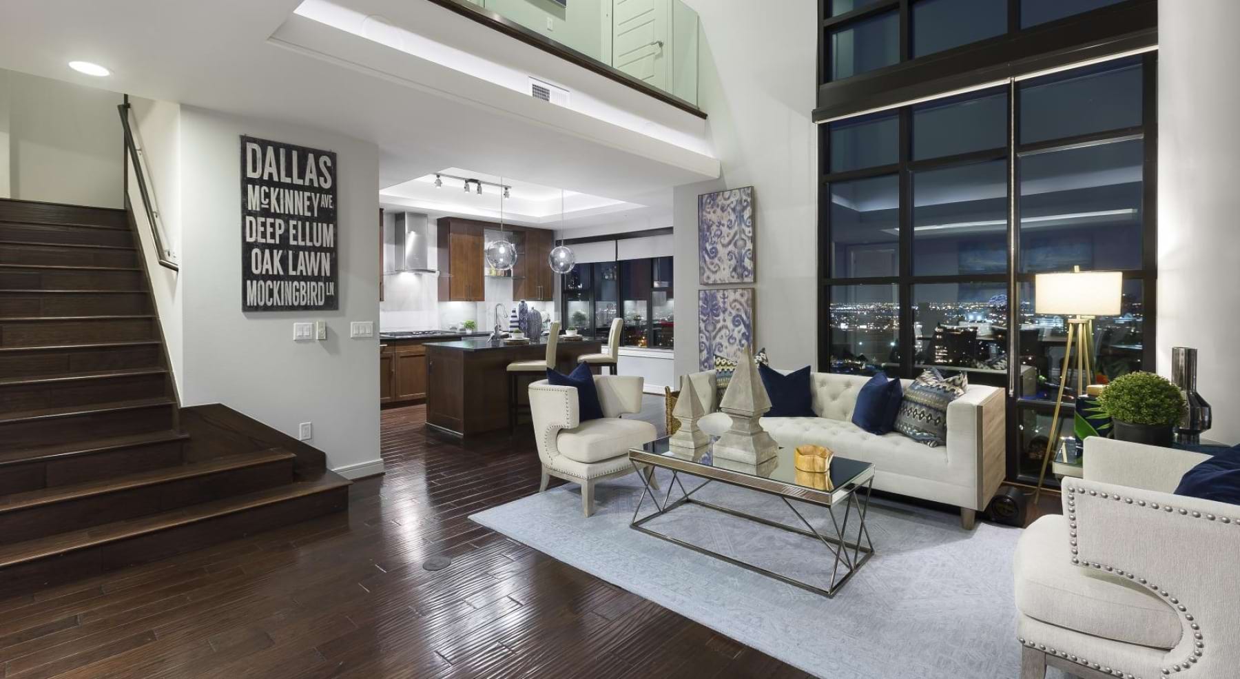 a room with a wood floor and white couches and a wood staircase